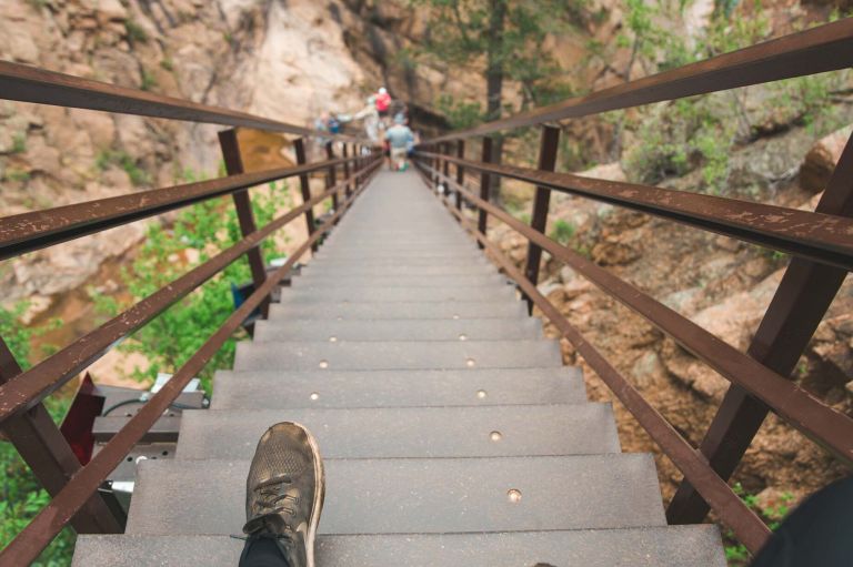A Group Of People Walking On A Bridge Over A River